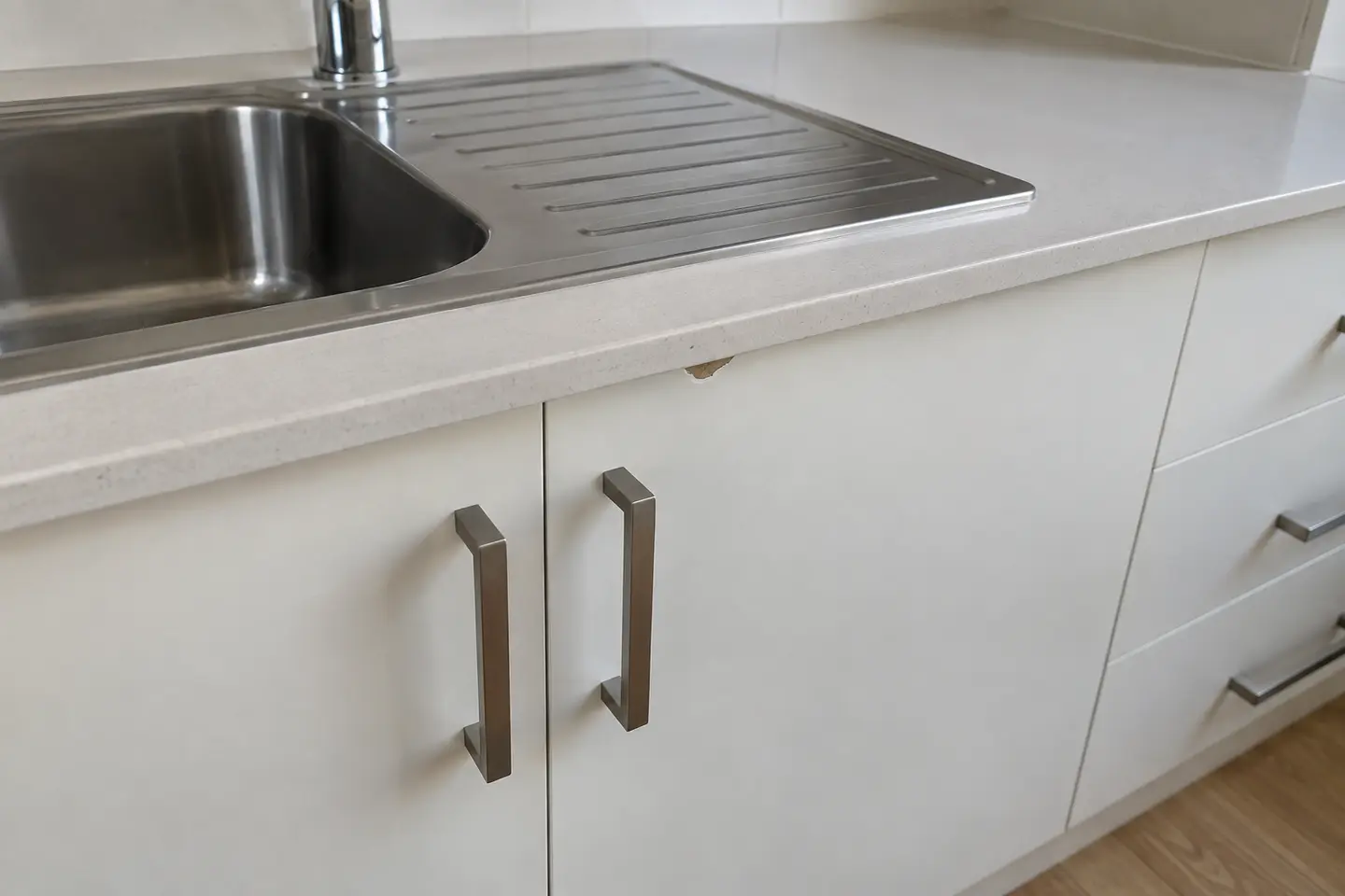 Close-up demonstration photo of a small chip near a kitchen sink
